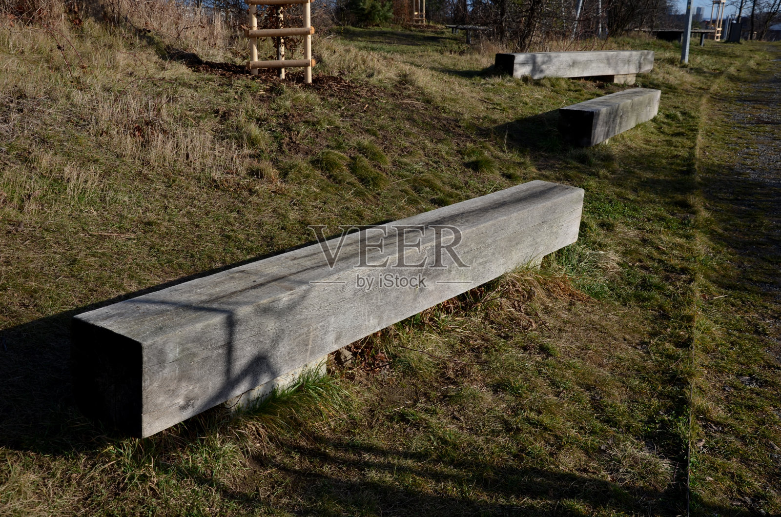 冬天公园里的木凳。立方体和石块也从采石场的粗石灰石块。草坪上的螺旋桨形状的长凳。覆盖物砾石中的观赏草照片摄影图片