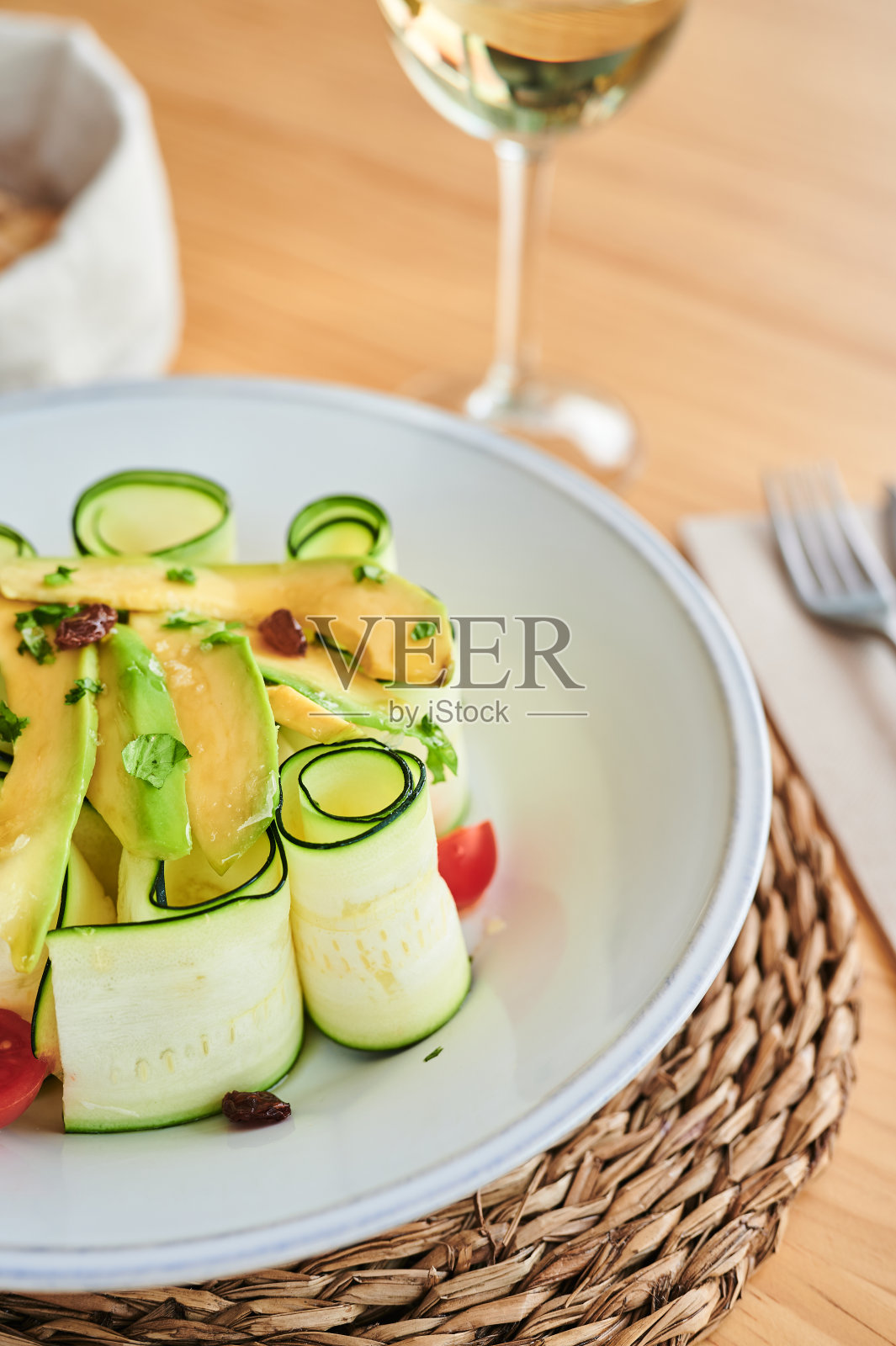 垂直高角度的新鲜西葫芦卷，盛在碗里，配有鳄梨片和半瓣圣女果照片摄影图片