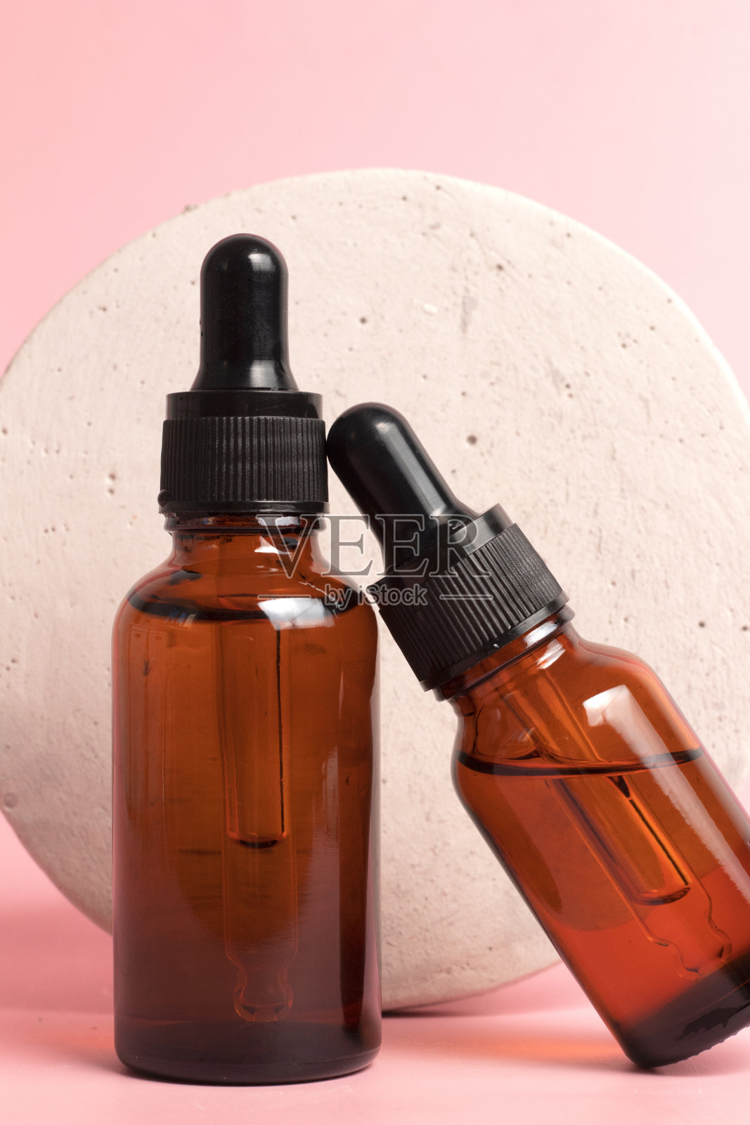 玻璃滴瓶，石制讲台上的粉红色背景。护肤品，天然化妆品。面部和身体护理的美容理念照片摄影图片