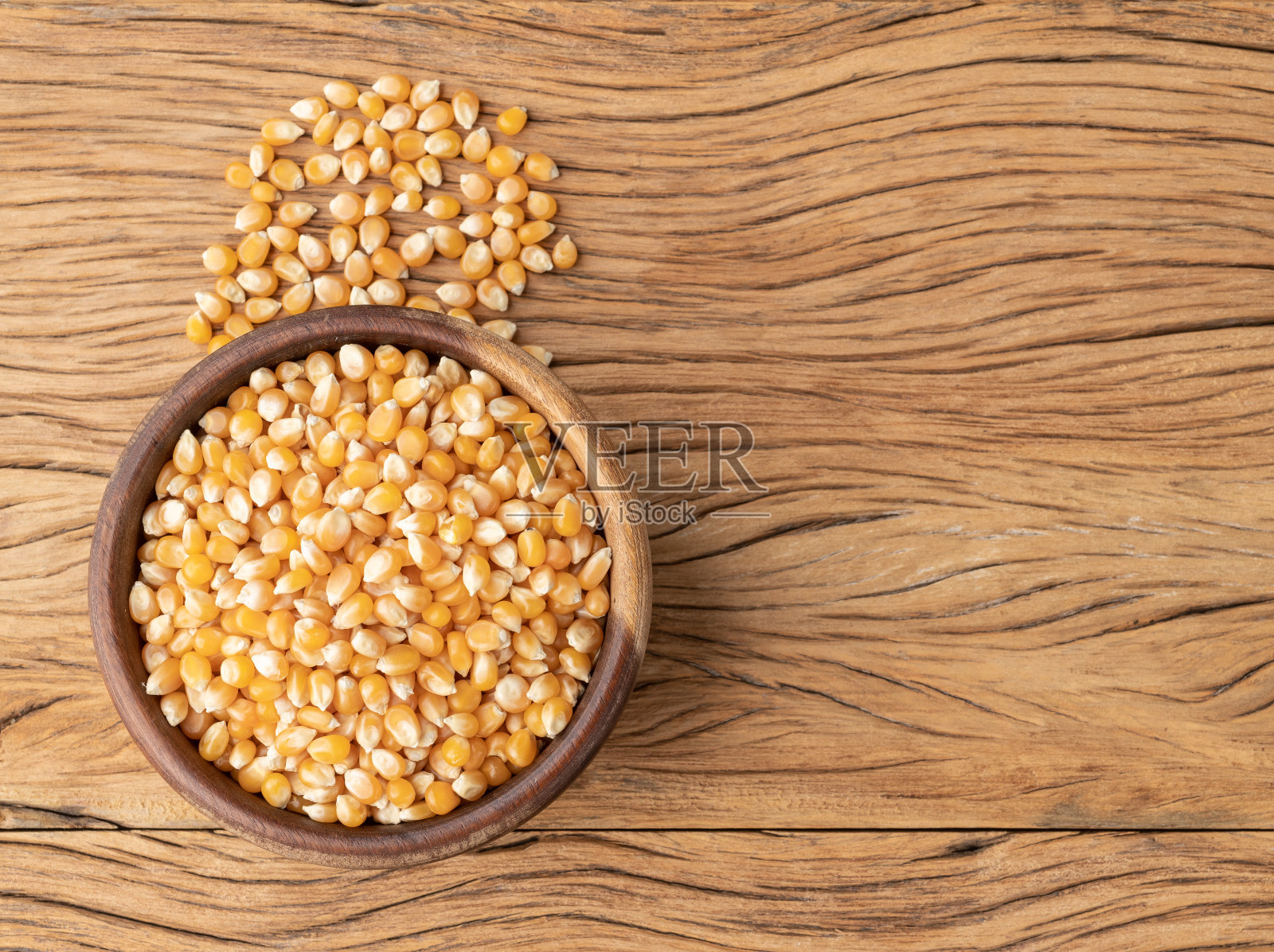 把干玉米或爆米花放在碗里，放在有复印空间的木桌上照片摄影图片