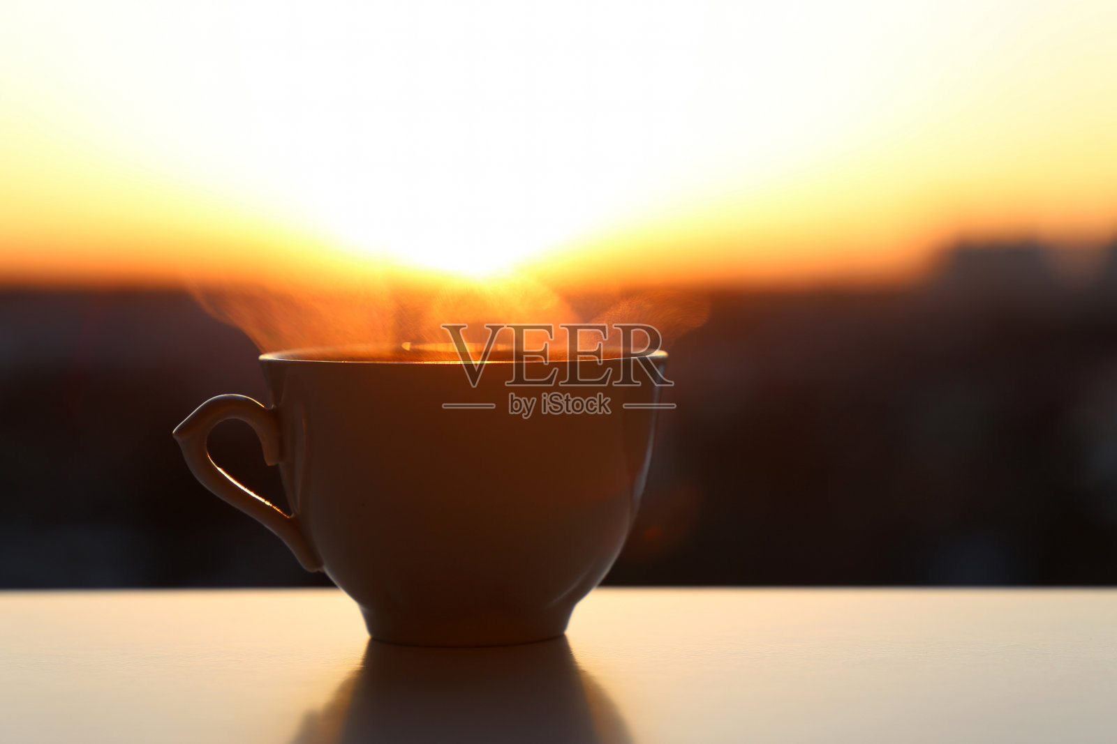 热咖啡杯，日出的背景上有烟照片摄影图片