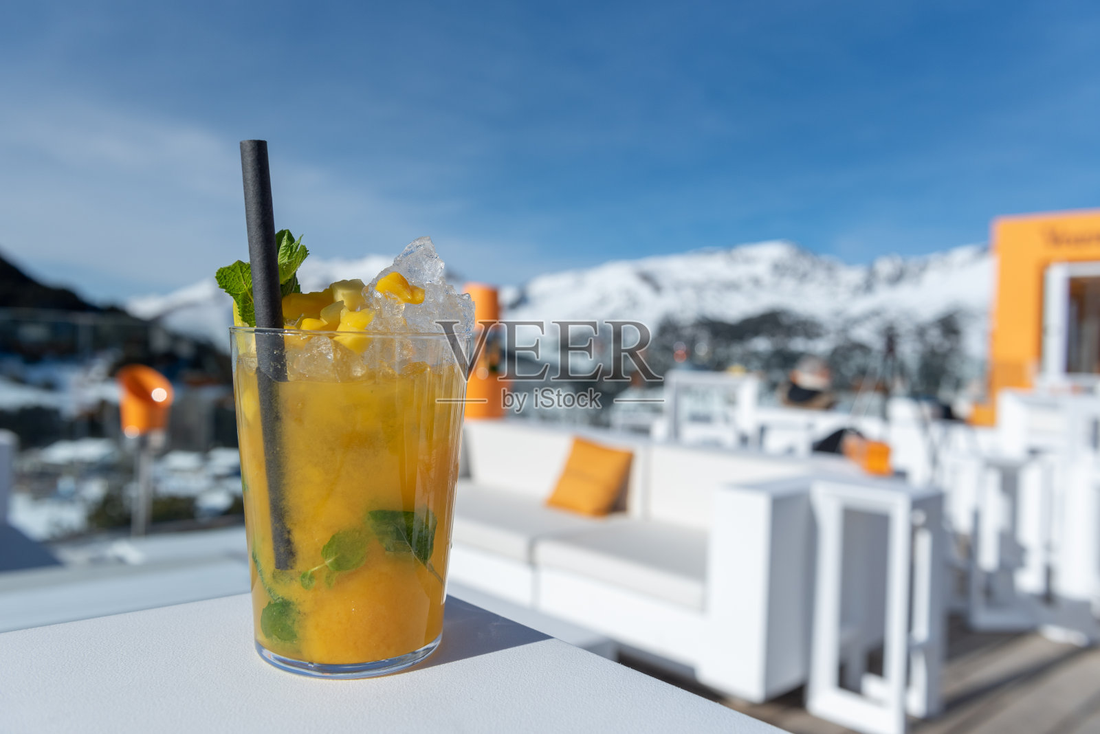 在一个阳光明媚的日子里，在滑雪场喝芒果鸡尾酒照片摄影图片