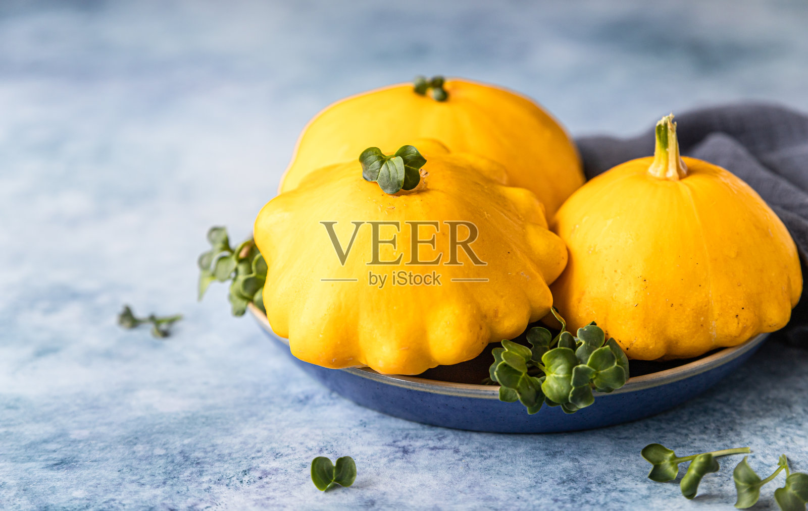 新鲜成熟的黄色patissons，南瓜或碟形南瓜在蓝色混凝土背景。收获有机蔬菜。照片摄影图片