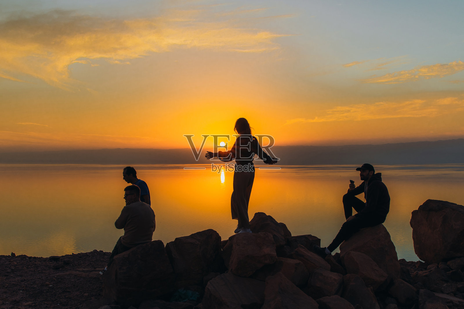 朋友们在约旦死海上欣赏日落美景的剪影照片摄影图片