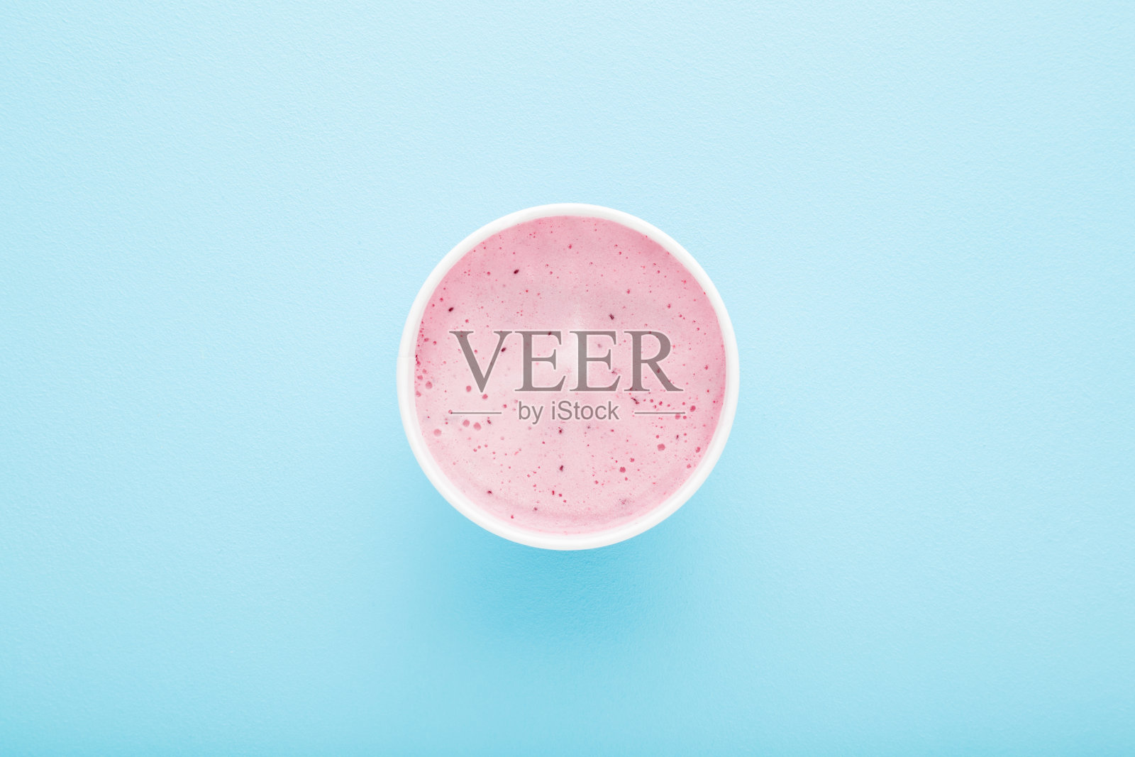 浅蓝色桌子背景上的白色纸杯浆果冰淇淋。柔和的颜色。特写镜头。夏天的冷甜点。自顶向下的观点。照片摄影图片