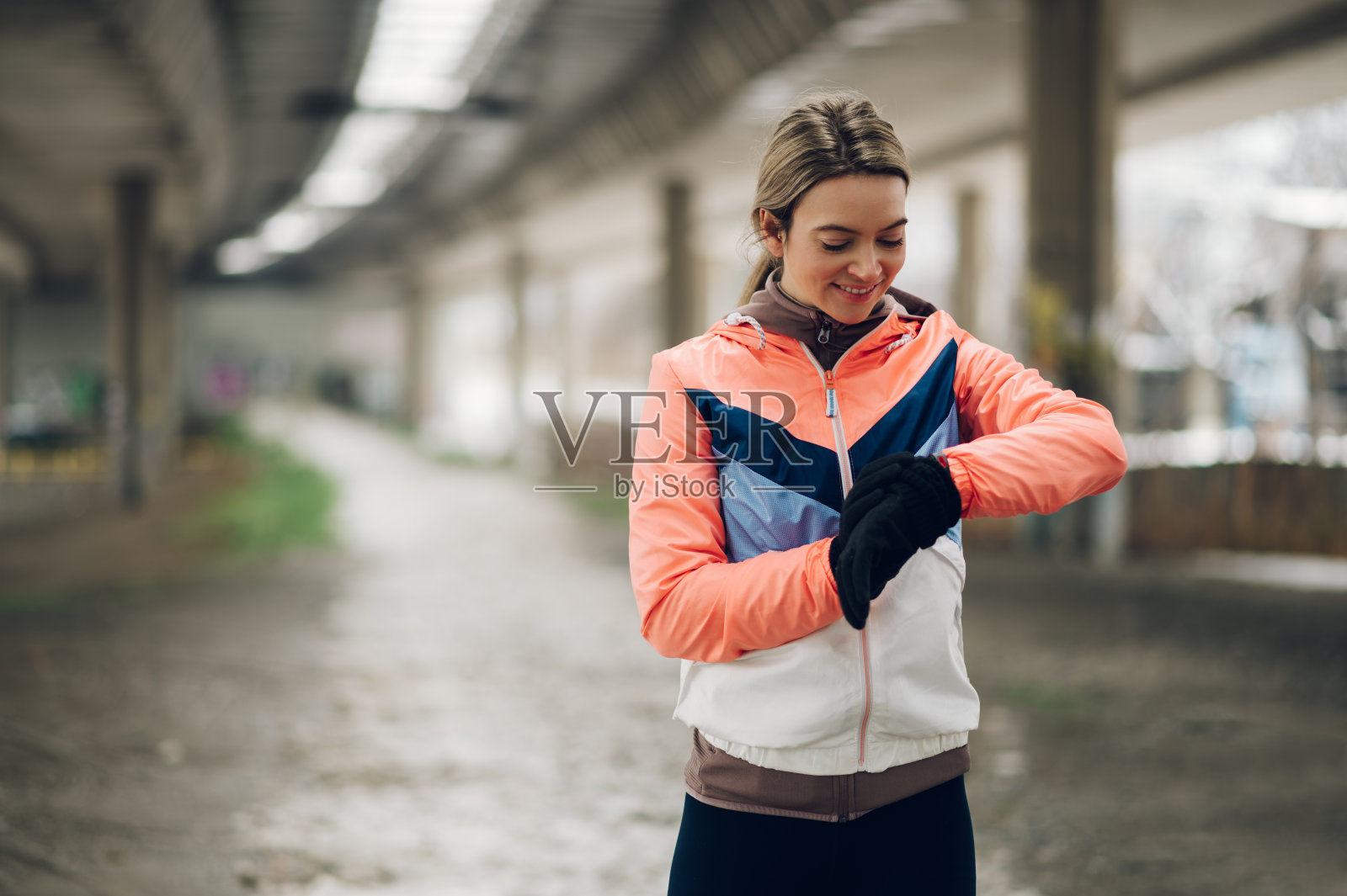 在寒冷的冬天，一名年轻女子在户外跑步时使用智能手表照片摄影图片