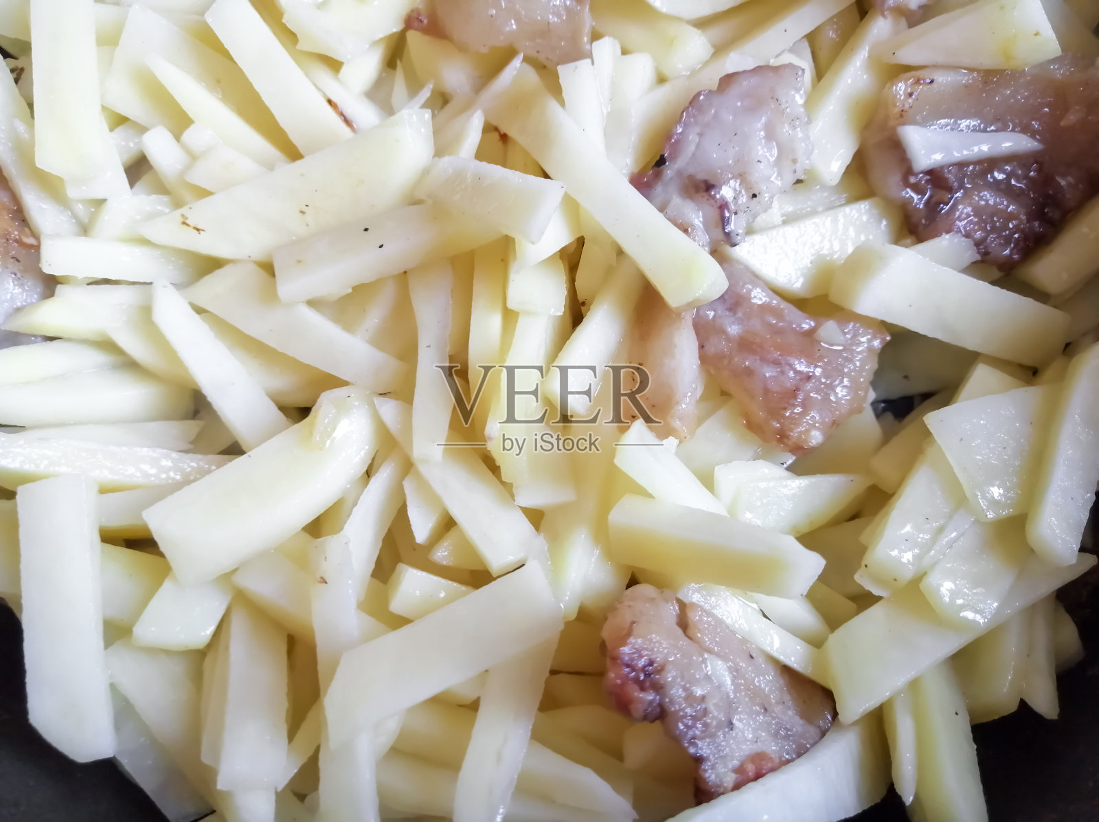 用吸管切的土豆用勺子油炸。熏肉和土豆。照片摄影图片