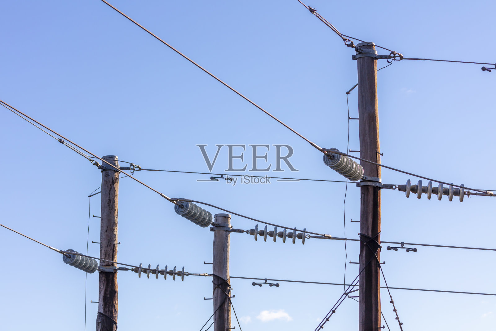 图为蓝色天空下的木制电话柱和电缆照片摄影图片