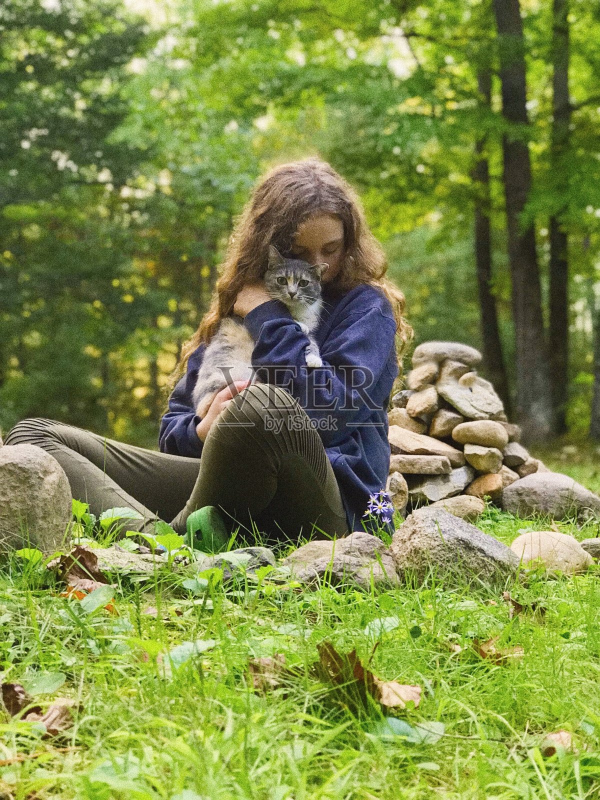 美丽的年轻少年拥抱她的猫，而坐在户外。照片摄影图片