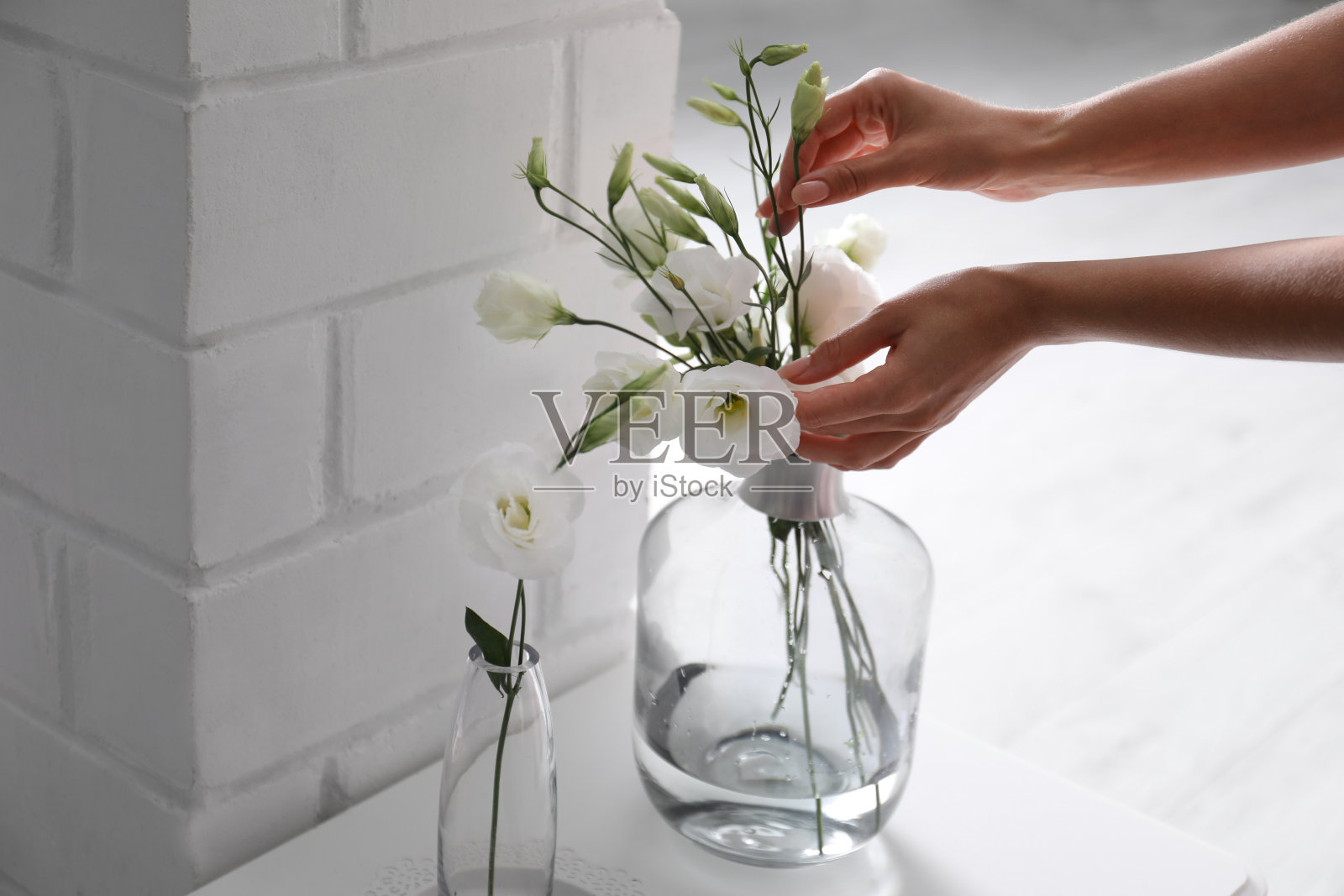 女人从室内的花瓶里拿着漂亮的花，特写镜头照片摄影图片