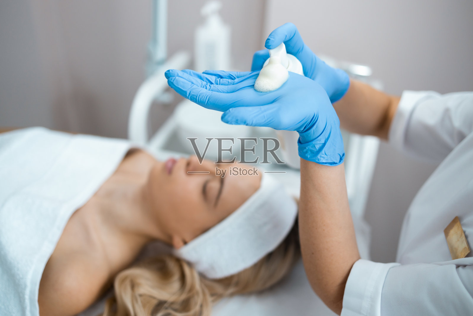 美容师医生在美容诊所为金发女性客户做抗衰老手术，面膜和脱皮照片摄影图片