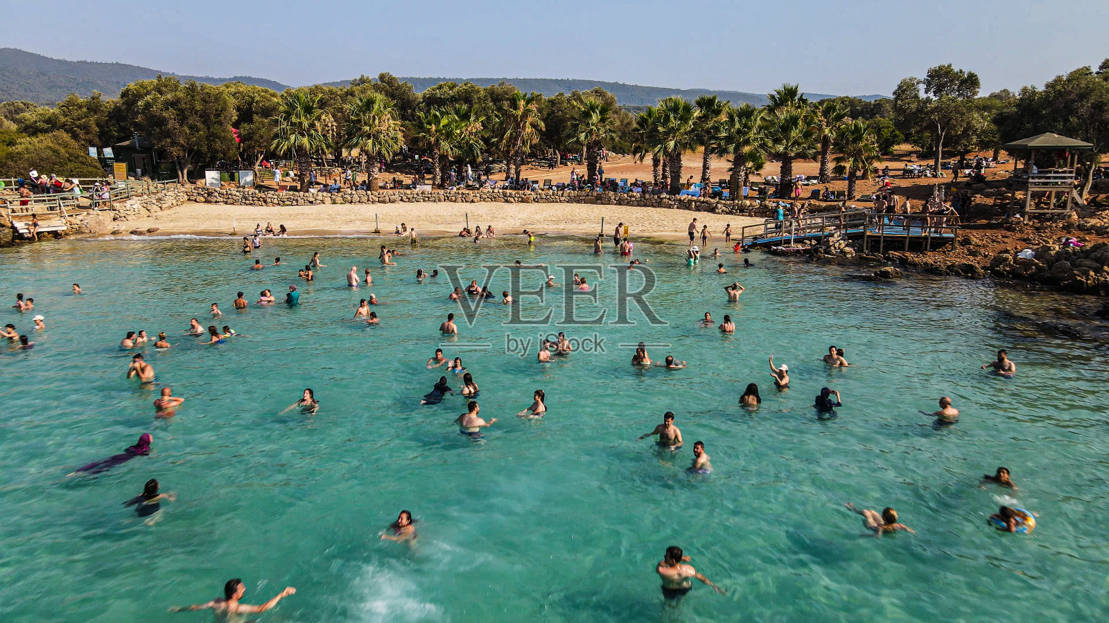 鸟瞰图人在海中游泳，受欢迎的岛屿，人群在蓝绿色的海中游泳，人在岛中游泳，人群，夏季活动，著名的夏季目的地，树之间的海滩照片摄影图片
