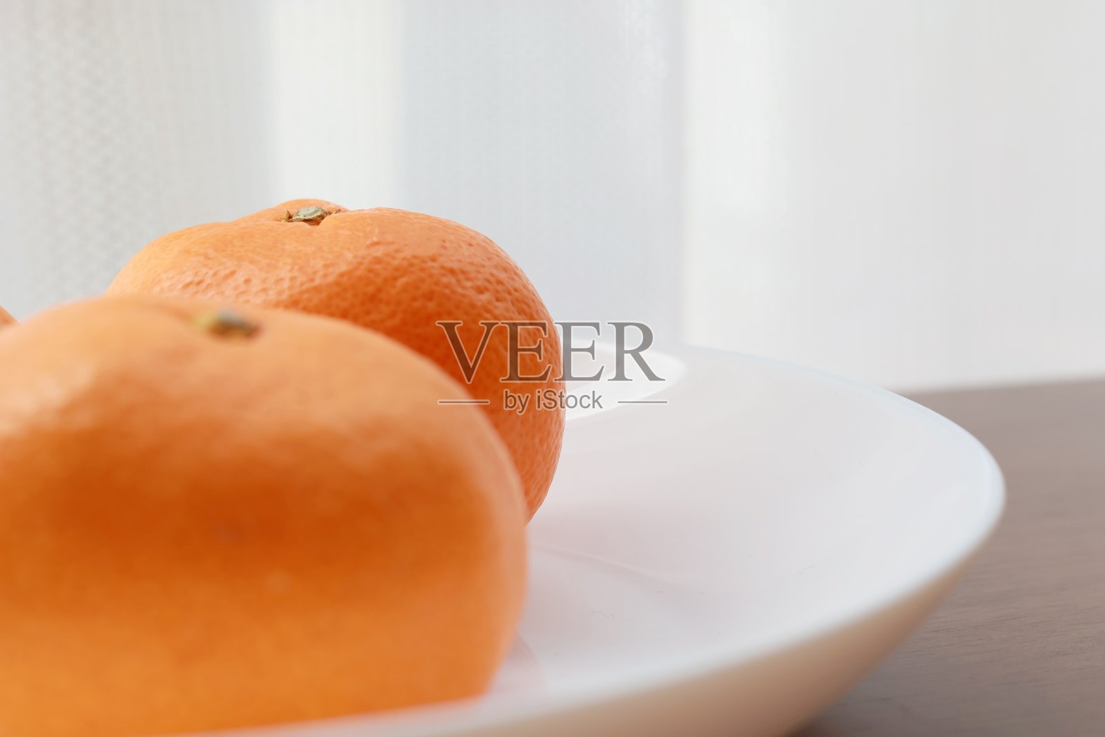 桌上放着白色盘子里的橘子照片摄影图片