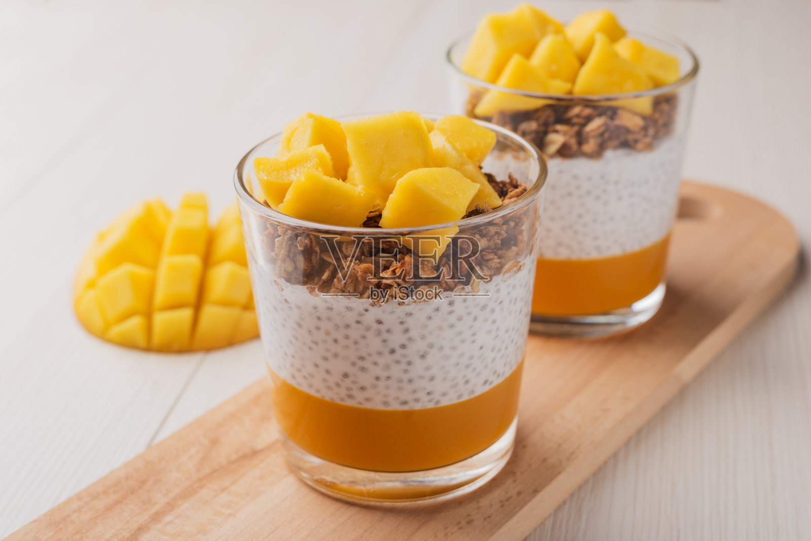 合上奇亚籽布丁与新鲜芒果，格兰诺拉麦片在玻璃随时可以吃。健康的早餐。带有复制空间的超级食物概念。照片摄影图片