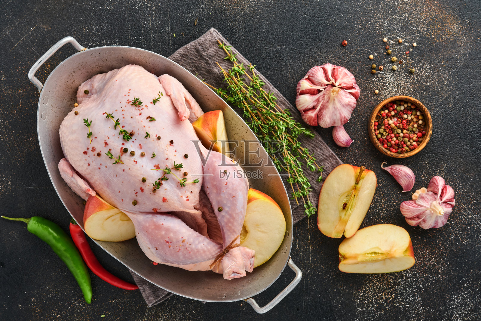 整只生鸡肉，配料用于制作玫瑰胡椒，柠檬，百里香，大蒜，樱桃番茄，酸模，苹果和盐，在厨房石板，石头或混凝土背景上。俯视图拷贝空间照片摄影图片