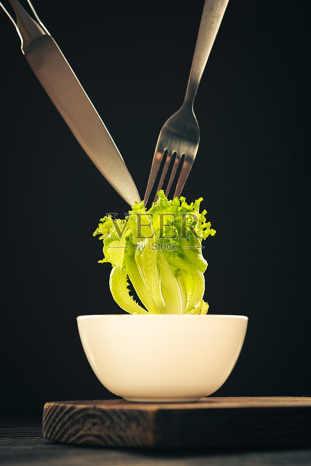 绿色沙拉与叉子和刀子在黑暗的背景照片摄影图片