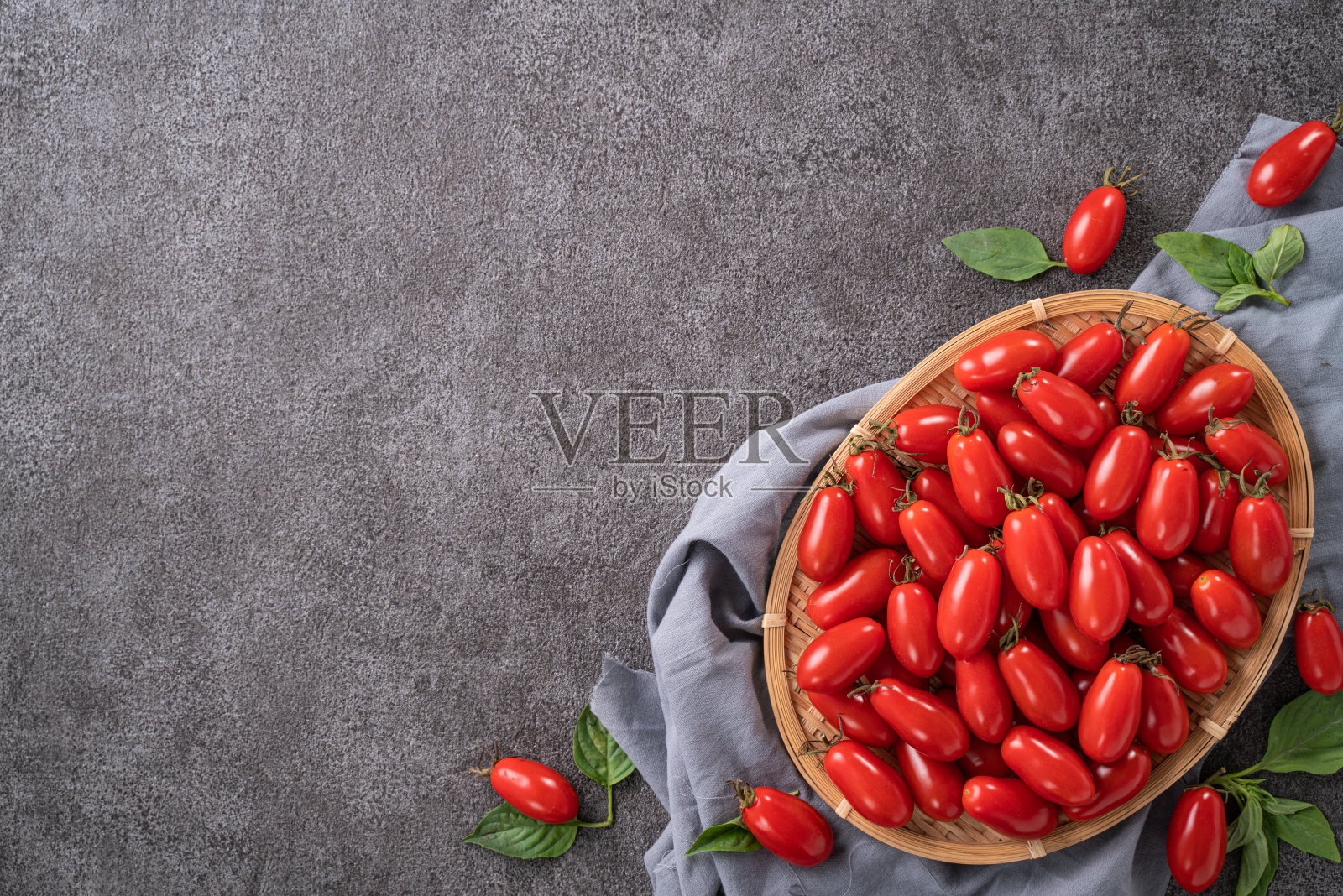 新鲜的圣女果和罗勒放在篮子里。照片摄影图片