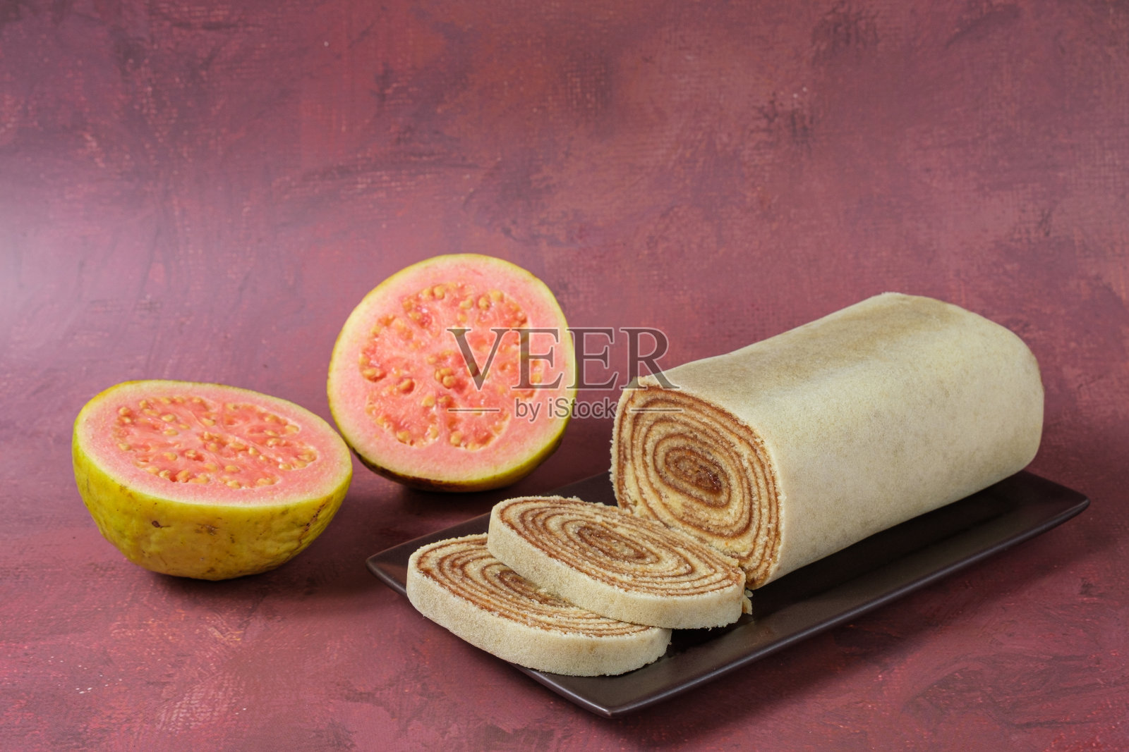 切成薄片放在棕色盘子里，旁边放着番石榴。照片摄影图片