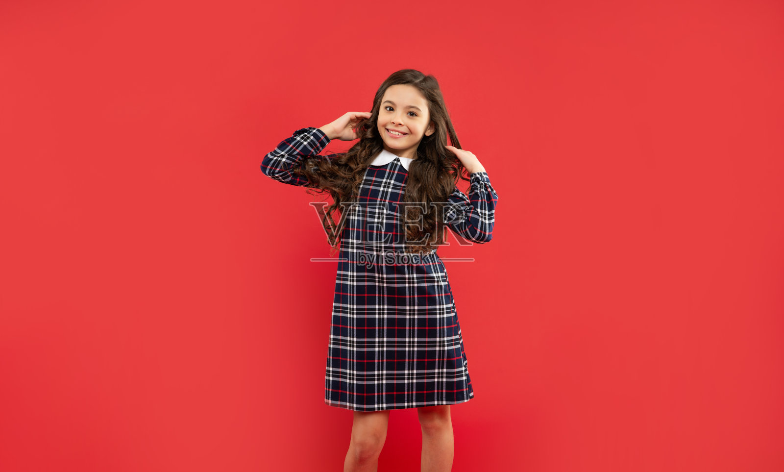 快乐的孩子，红色的背景，长长的卷发照片摄影图片