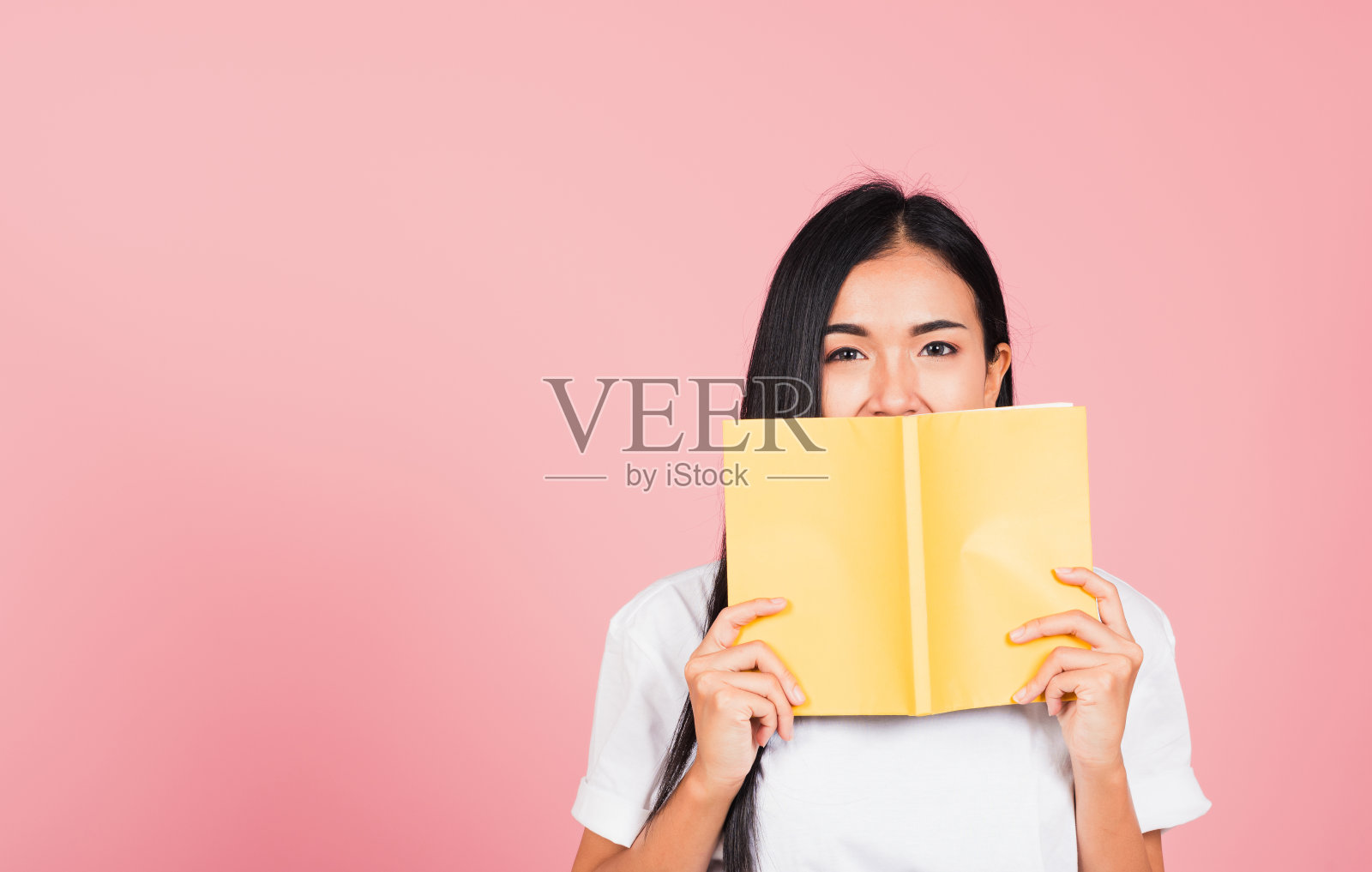 女人十几岁的微笑覆盖她的脸与黄皮书照片摄影图片