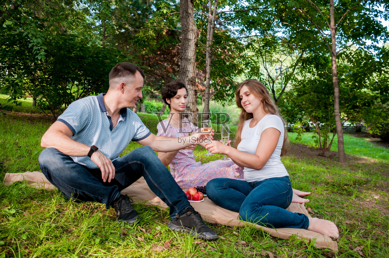 一个男人在公园的夏季野餐上招待两个女孩喝酒照片摄影图片