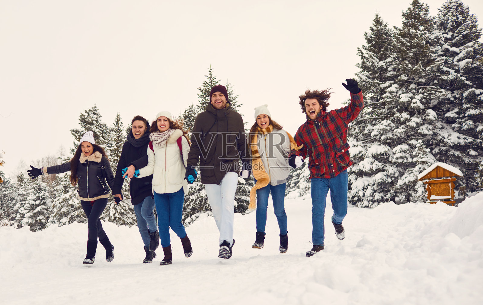 冬天，朋友们在公园的雪地里奔跑照片摄影图片