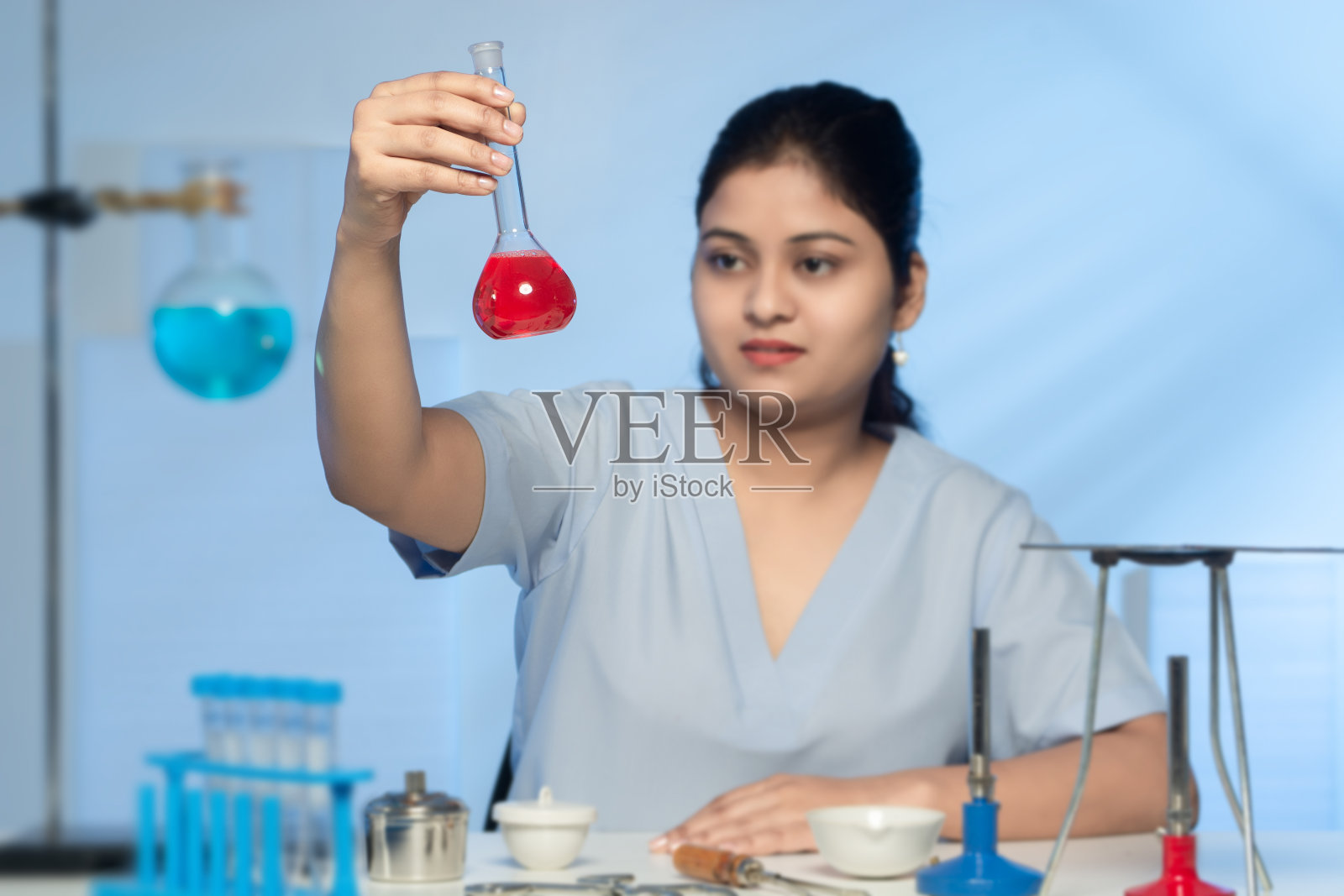 年轻的亚裔印度女实验室技术人员穿着天蓝色制服在研究实验室工作照片摄影图片