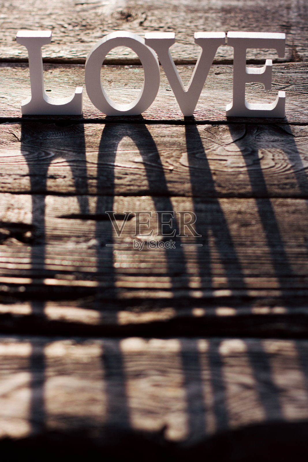 “爱”这个词是用白色的字母在棕色的木制背景上拼成的。情人节，爱心，环保材料照片摄影图片