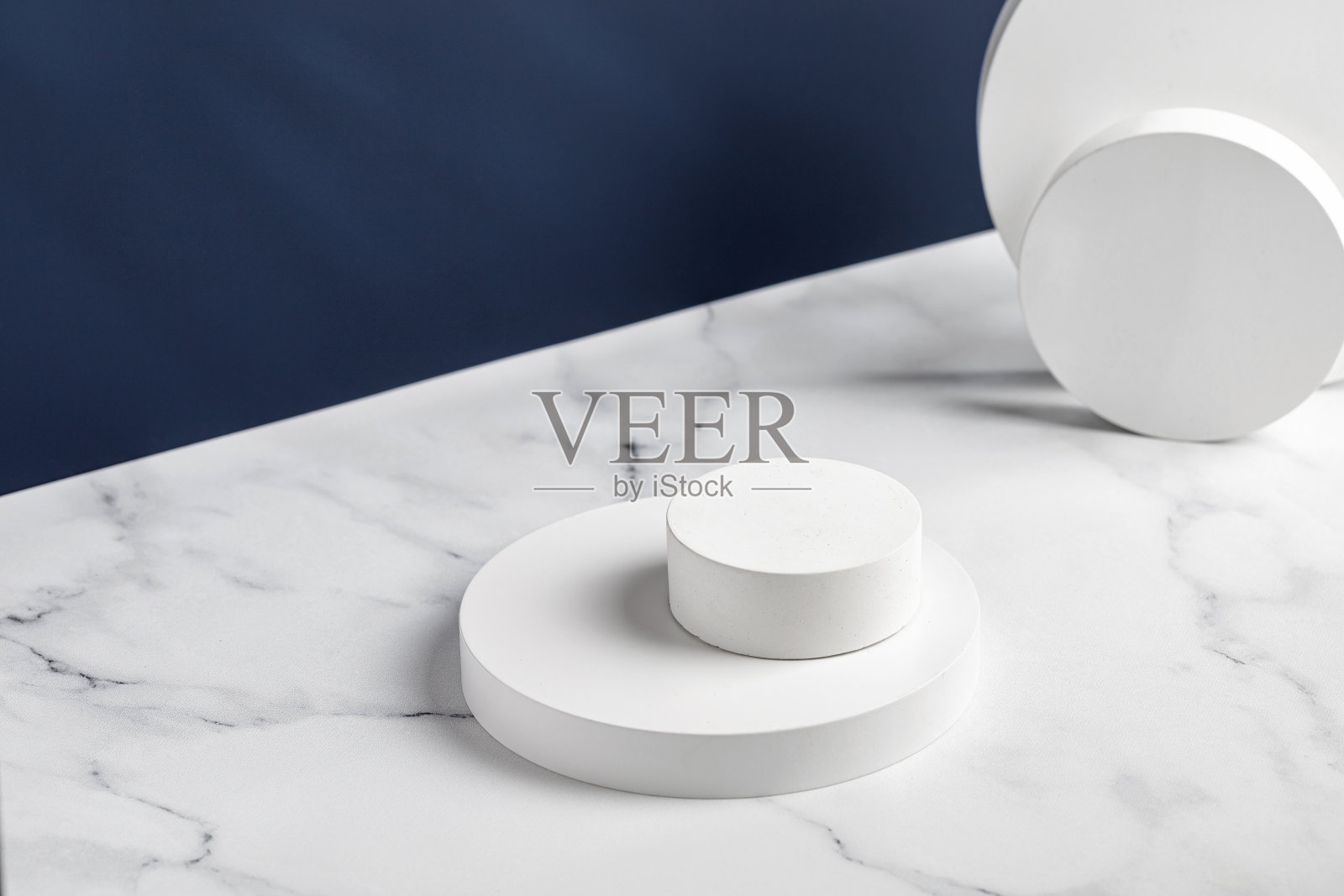 裙房。白色圆形讲台用于展示和化妆。自然美丽底座在白色大理石背景。蓝色的墙。照片摄影图片