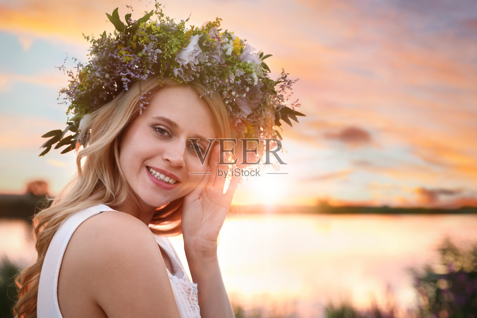 日落时分，一位年轻女子戴着由美丽的花朵制成的花环在户外照片摄影图片