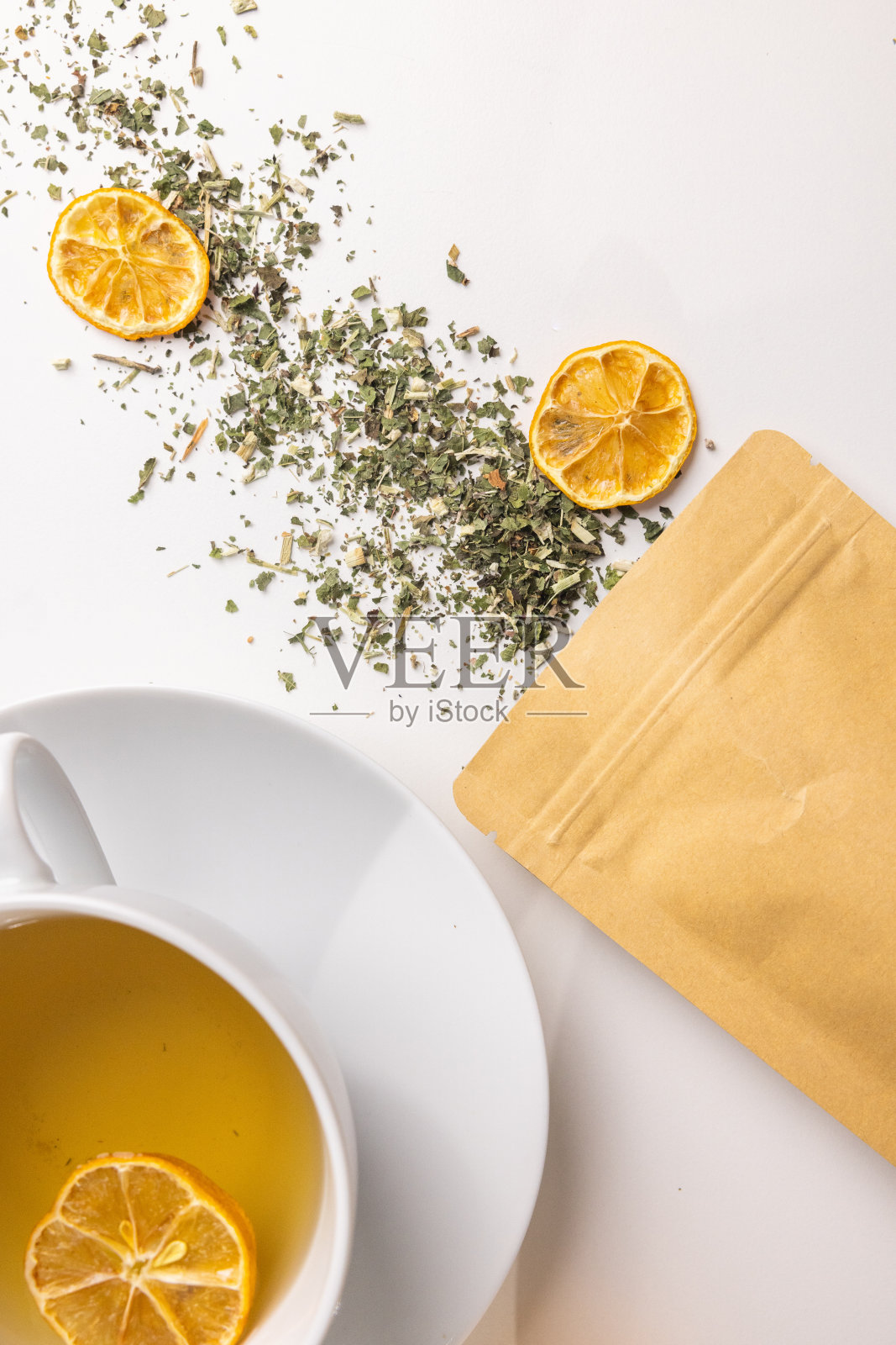 桌上放着一杯茶，上面放着香草、鲜花和一片柠檬干照片摄影图片