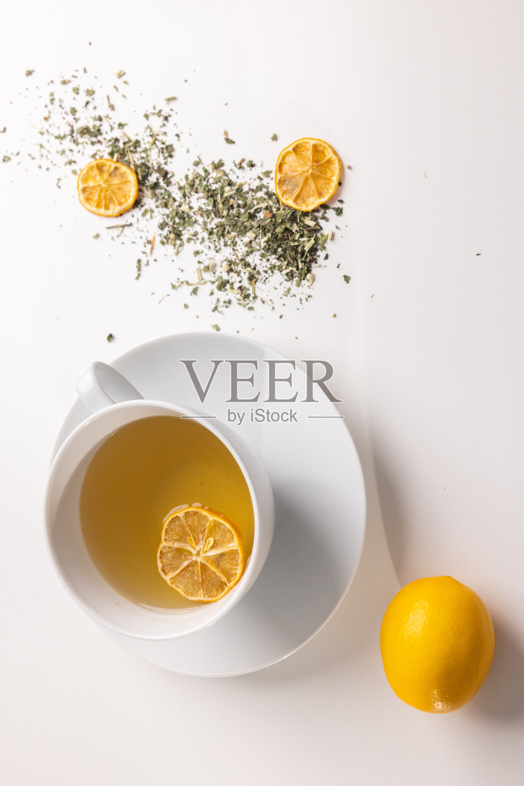 桌上放着一杯茶，上面放着香草、鲜花和一片柠檬干照片摄影图片
