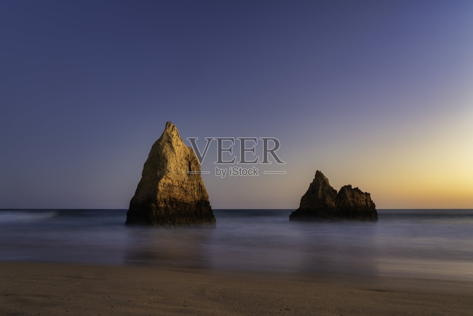 日落时分，在葡萄牙阿尔加维的阿尔沃海滩，岩石被点亮照片摄影图片