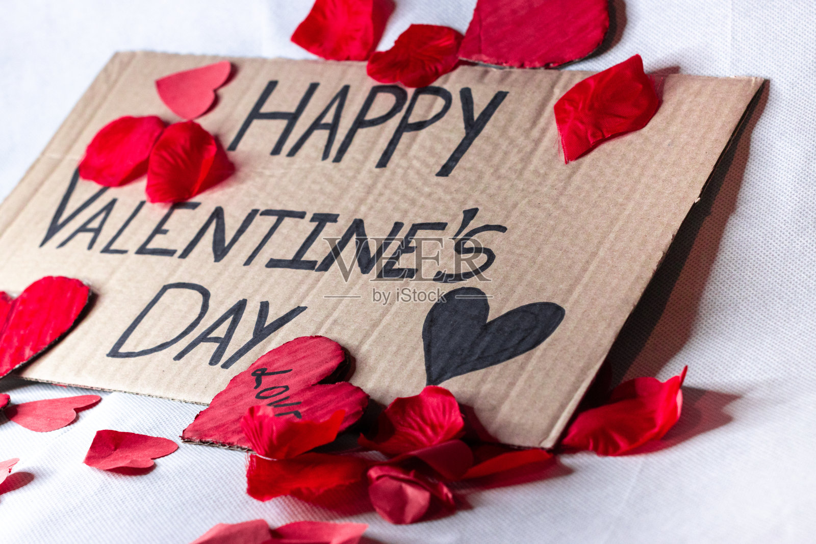 情人节快乐海报，白色背景上被红心和花瓣包围，选择性聚焦照片摄影图片