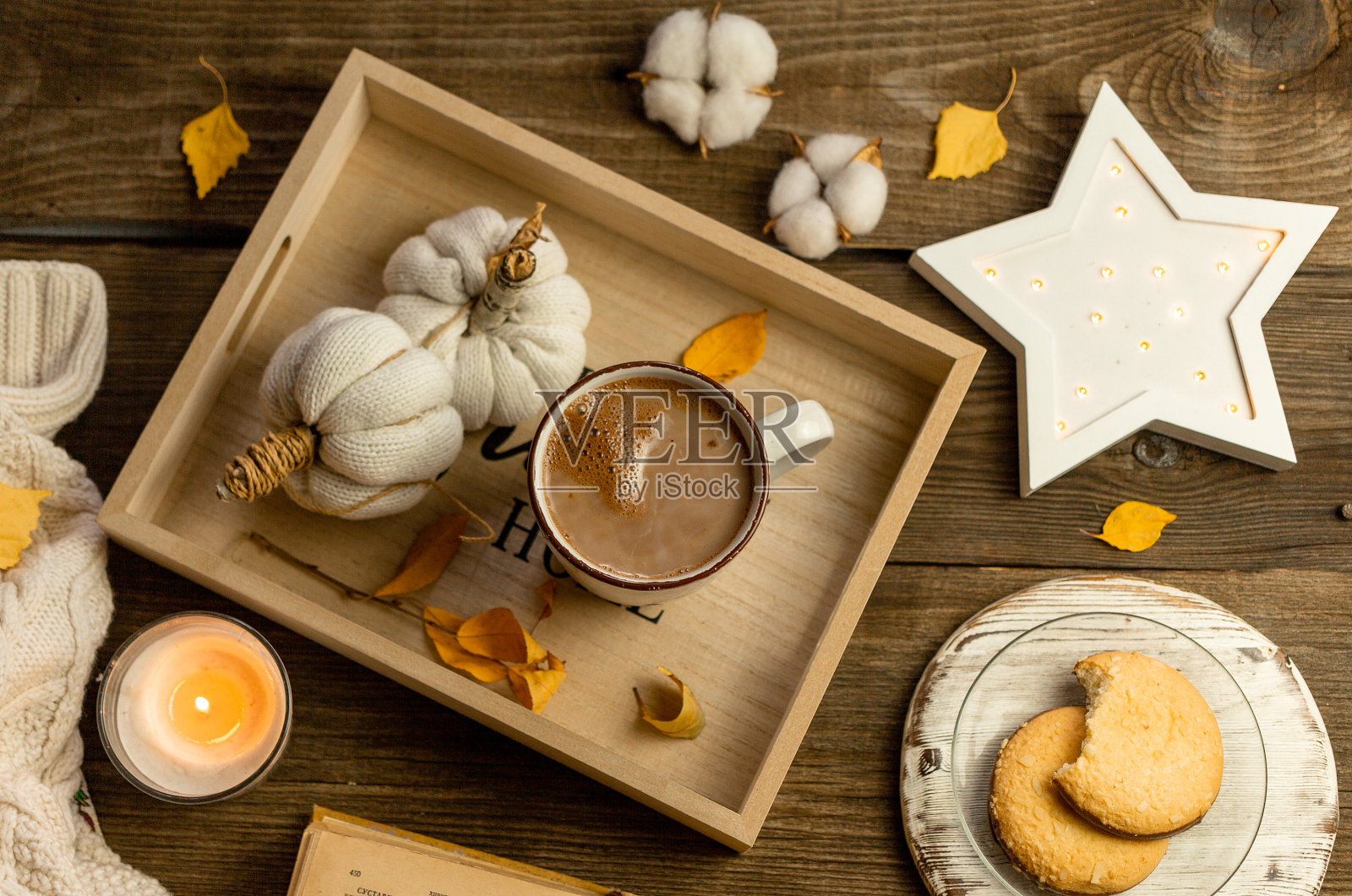 秋天的静物木托盘，手工编织的白色南瓜，黄色的叶子，一杯可可，咖啡或热巧克力，点燃的蜡烛，圆形的饼干。温馨家的舒适理念照片摄影图片