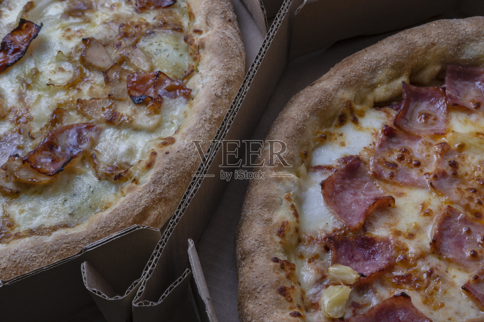 特写视图的两个披萨的纸箱。夏威夷卡博纳拉披萨配芝士，焦糖洋葱和培根。餐厅和快餐的促销概念。照片摄影图片