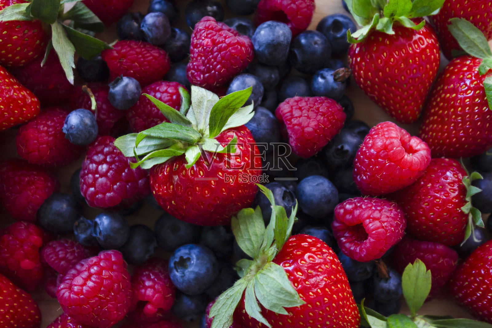 新鲜草莓、蓝莓和覆盆子。丰富多彩的新鲜森林水果背景。健康食品的概念。照片摄影图片