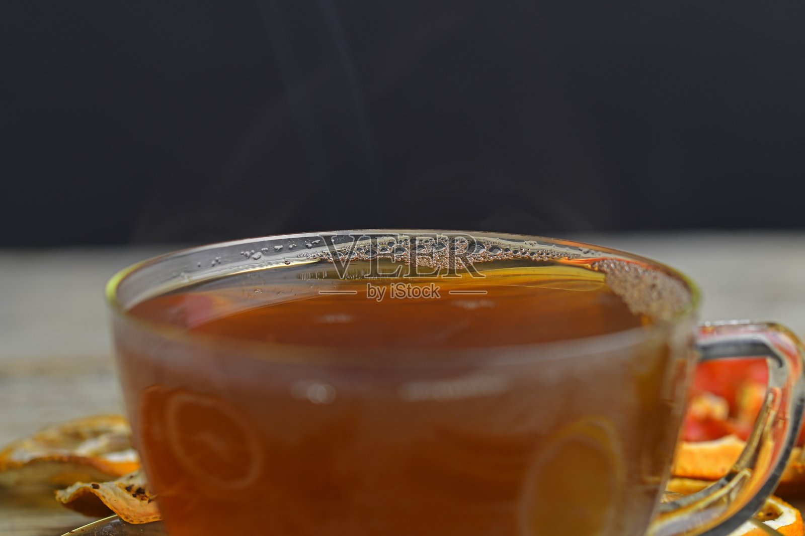 一杯热茶和蒸汽在黑色。一杯红茶与肉桂棒，八角星，柠檬和干果白色木制桌子背景。宏观形象照片摄影图片