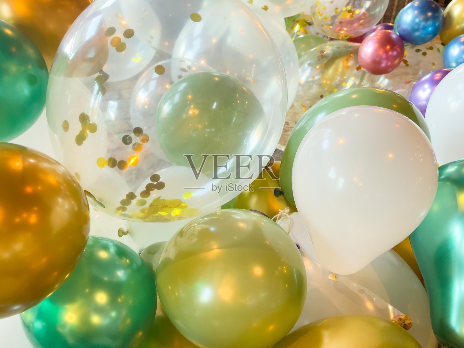 派对庆祝活动的彩色闪亮气球的特写——透明气球里面有金色的五彩纸屑，青色的，紫色的，绿色的，金色的气球都紧紧地绑在一起照片摄影图片