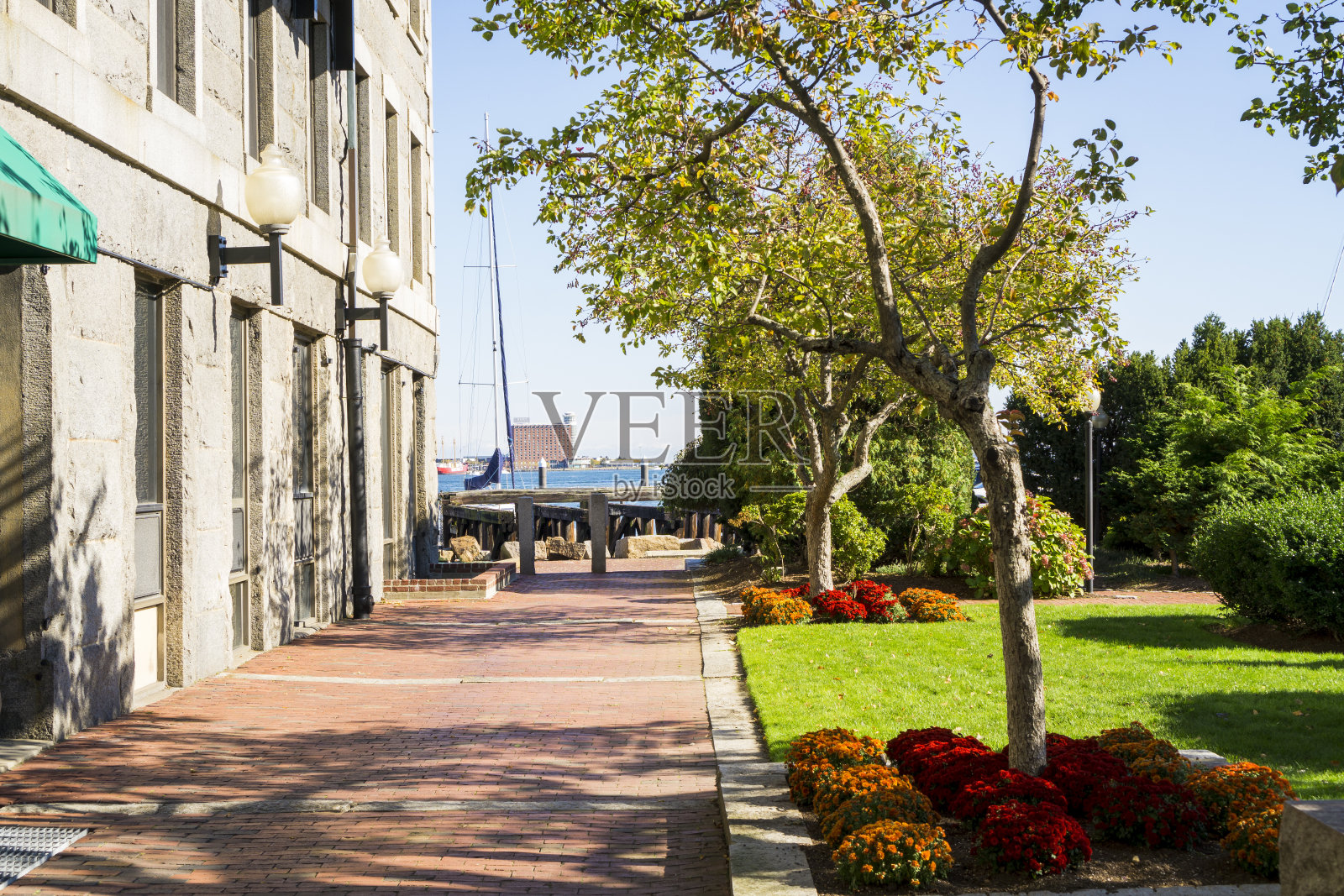 一侧是建筑立面的人行道，另一侧是树木和鲜花的公园照片摄影图片