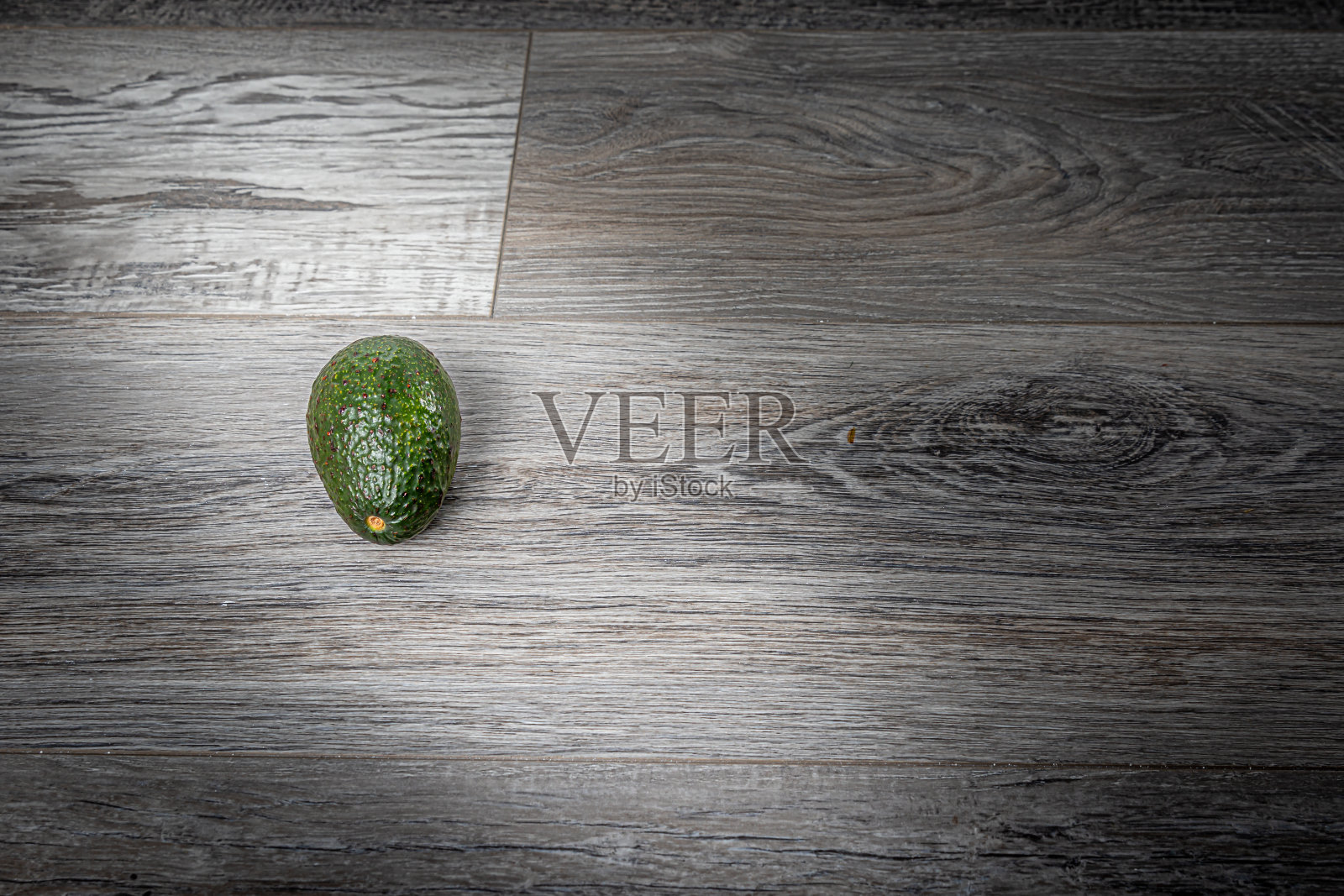 单个鳄梨在灰色木材表面与工作室照明照片摄影图片