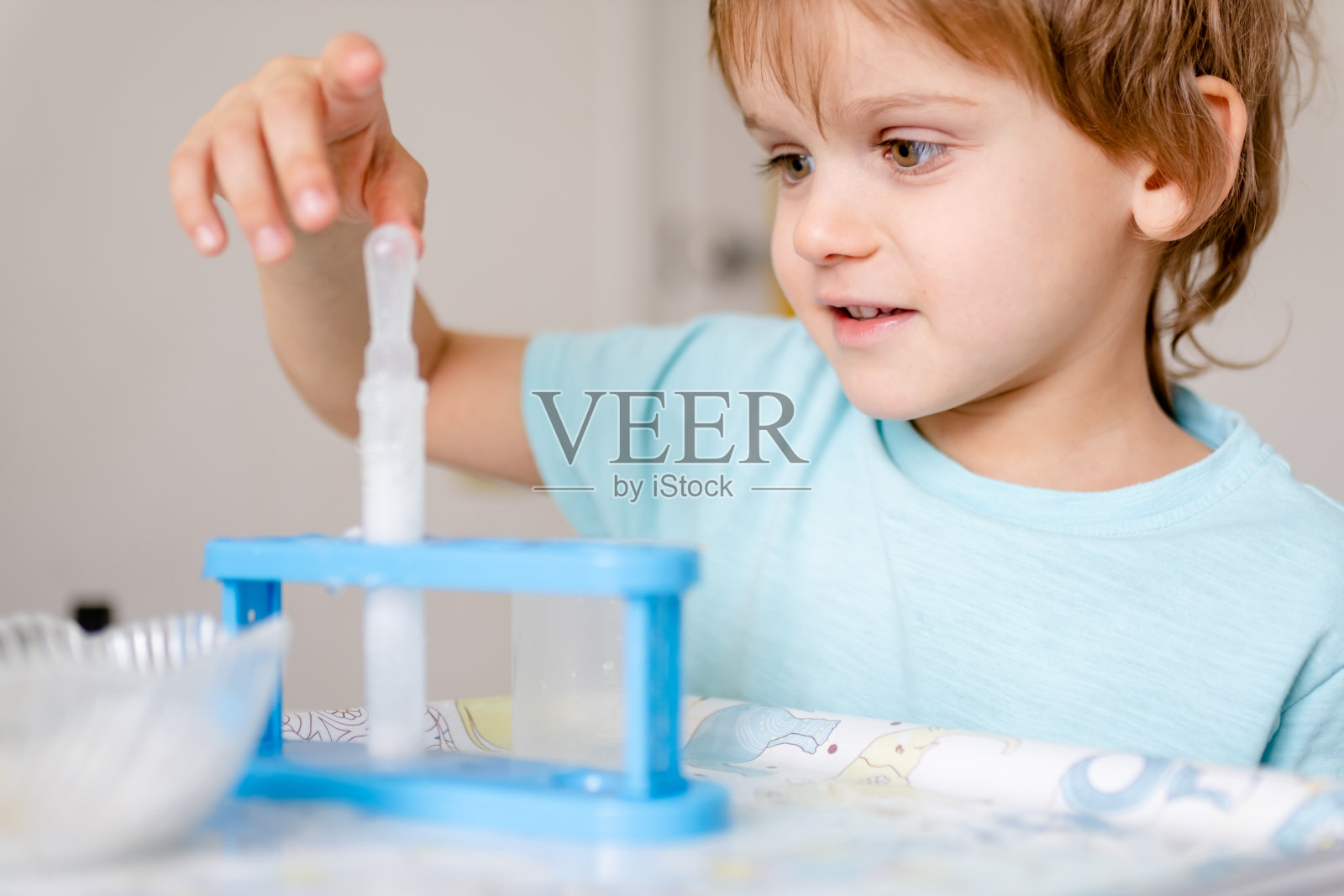 穿着蓝色t恤的快乐男孩在家里用醋和苏打水做化学实验照片摄影图片