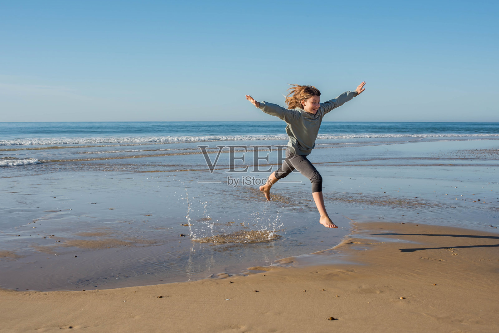 可爱的小女孩在沙滩度假玩和跳赤脚在沙滩上照片摄影图片