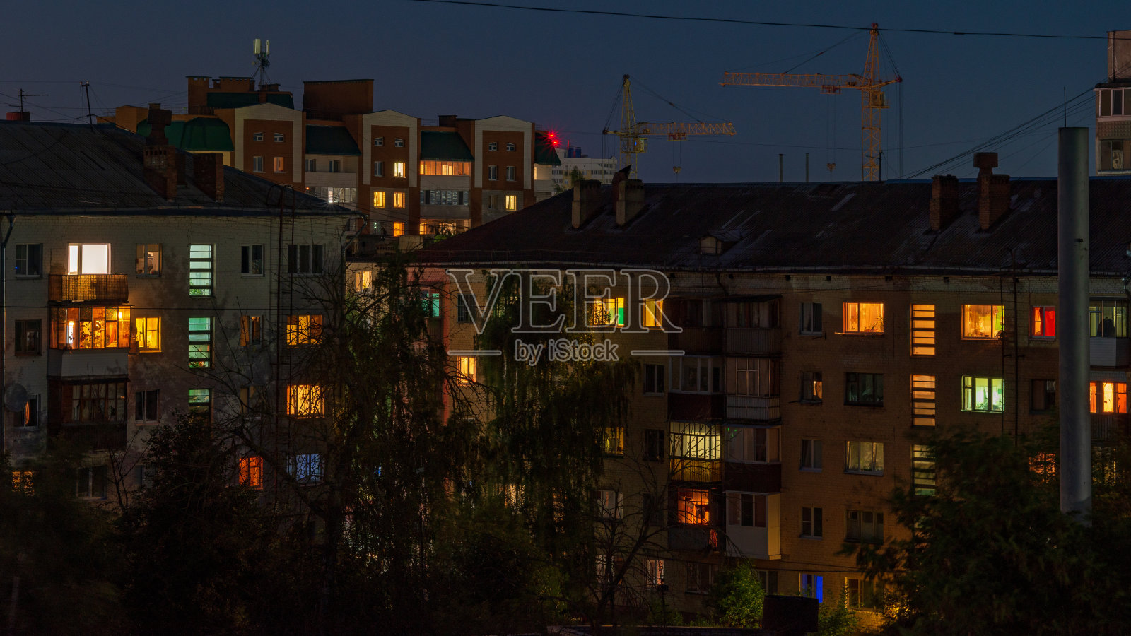 夏天的夜晚，高楼大厦的窗户上透出暖色调的光照片摄影图片