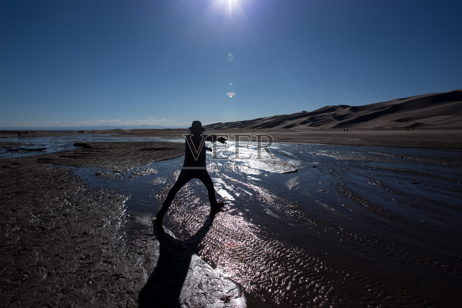 男子跃过水面，科罗拉多的大沙丘照片摄影图片