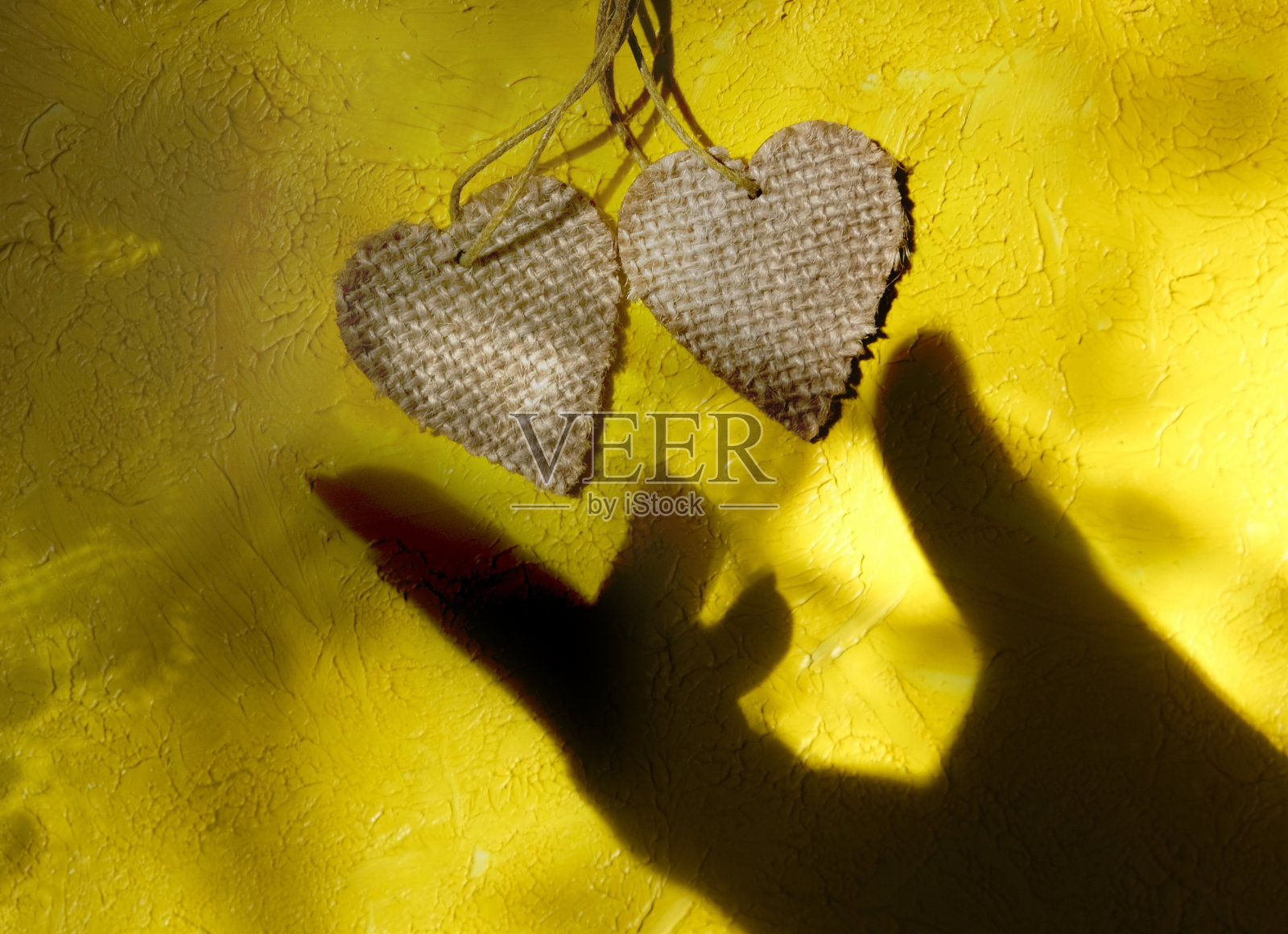 模糊阴影的女性手和两个木心粗糙的黄色墙壁背景。照片摄影图片