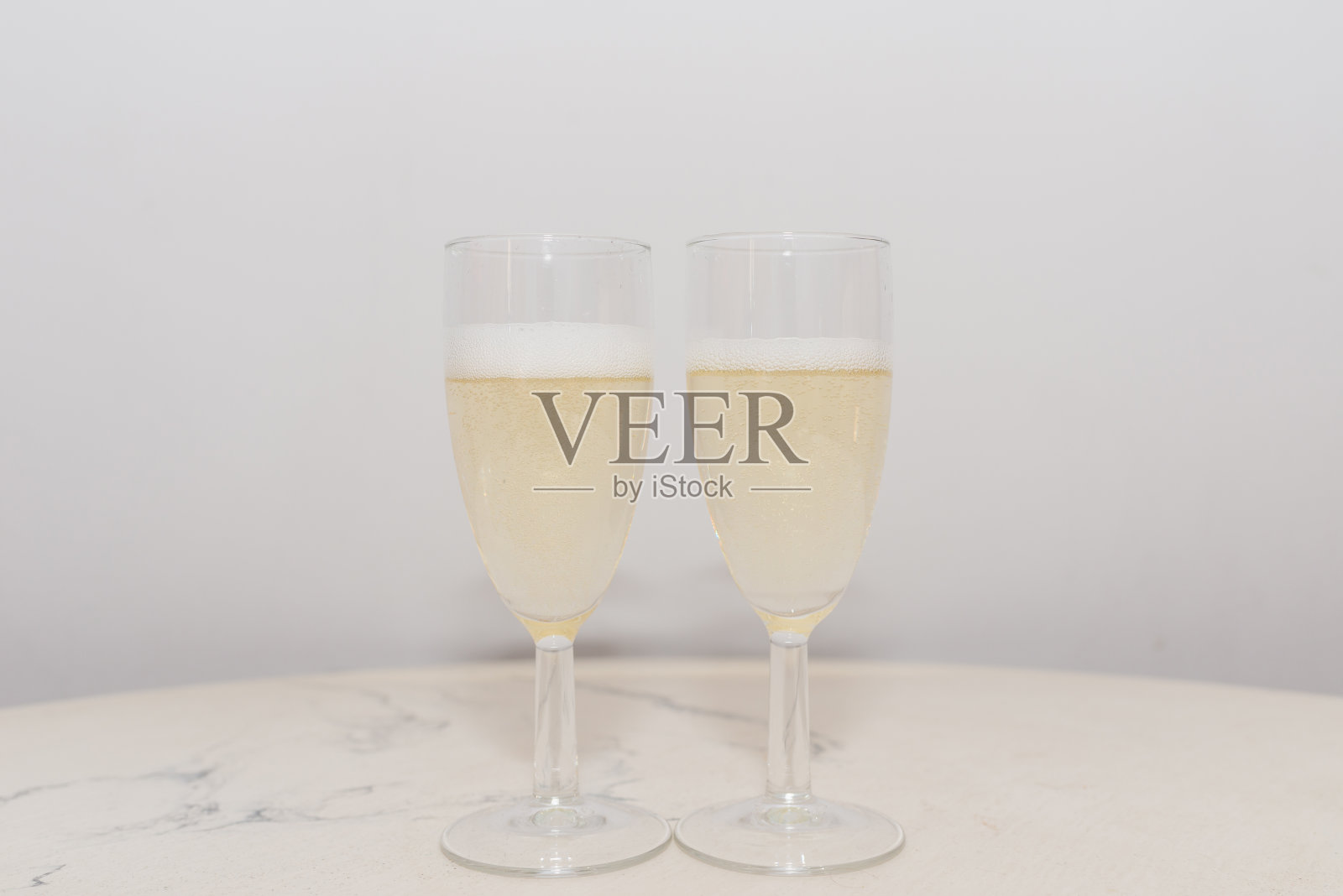 两个香槟玻璃泡沫放在桌子上的情人节或蜜月概念。在室内拍摄。照片摄影图片