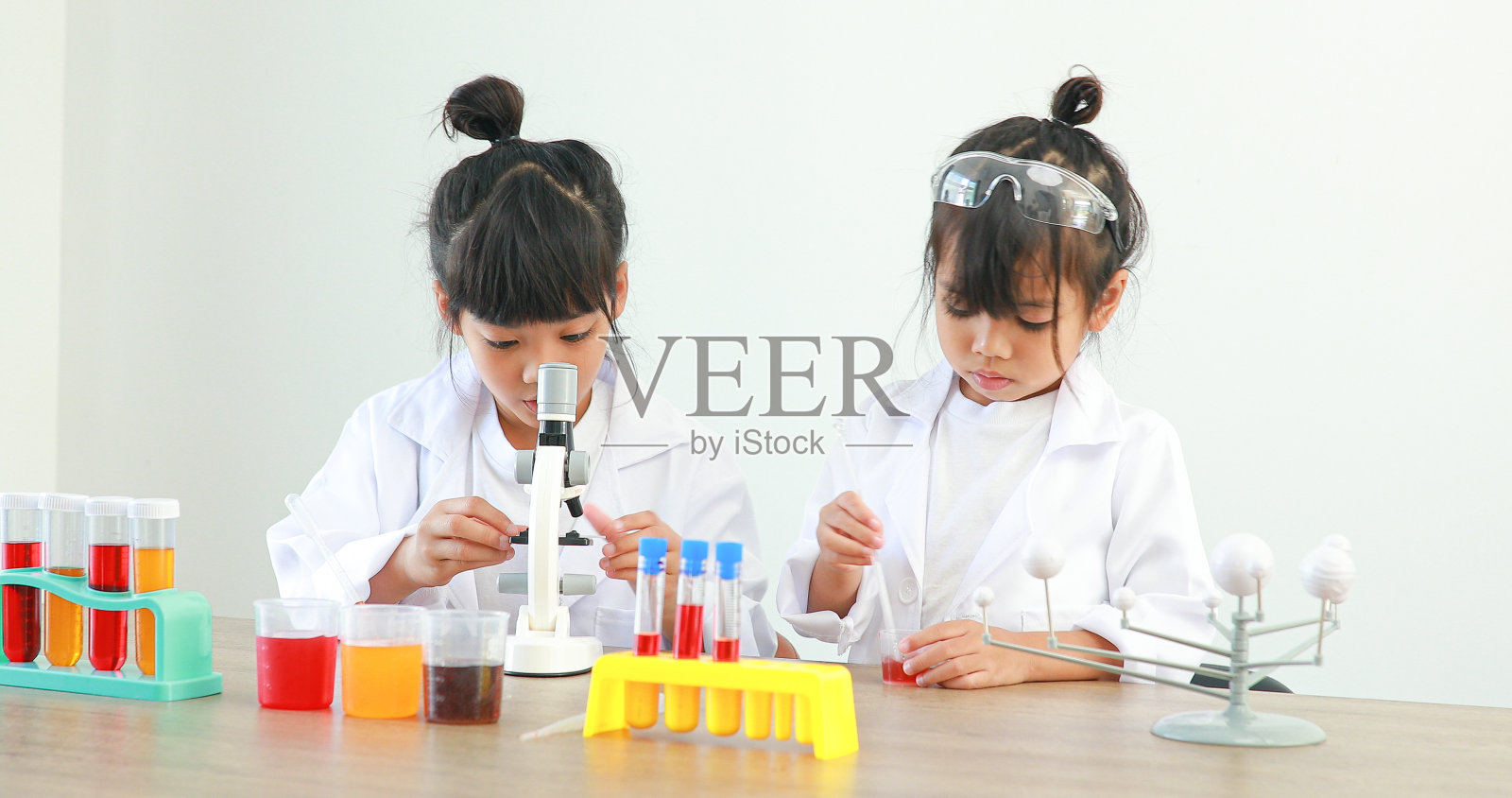 小女孩亚洲可爱的小学生学习研究和做化学实验，在家里的桌子上用试管分析和混合液体。照片摄影图片