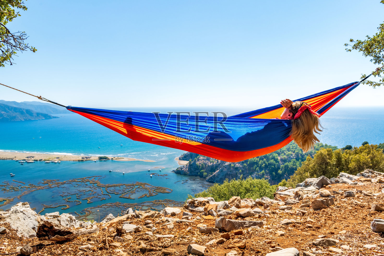 那个躺在吊床上的女人高兴地看着海滩。照片摄影图片