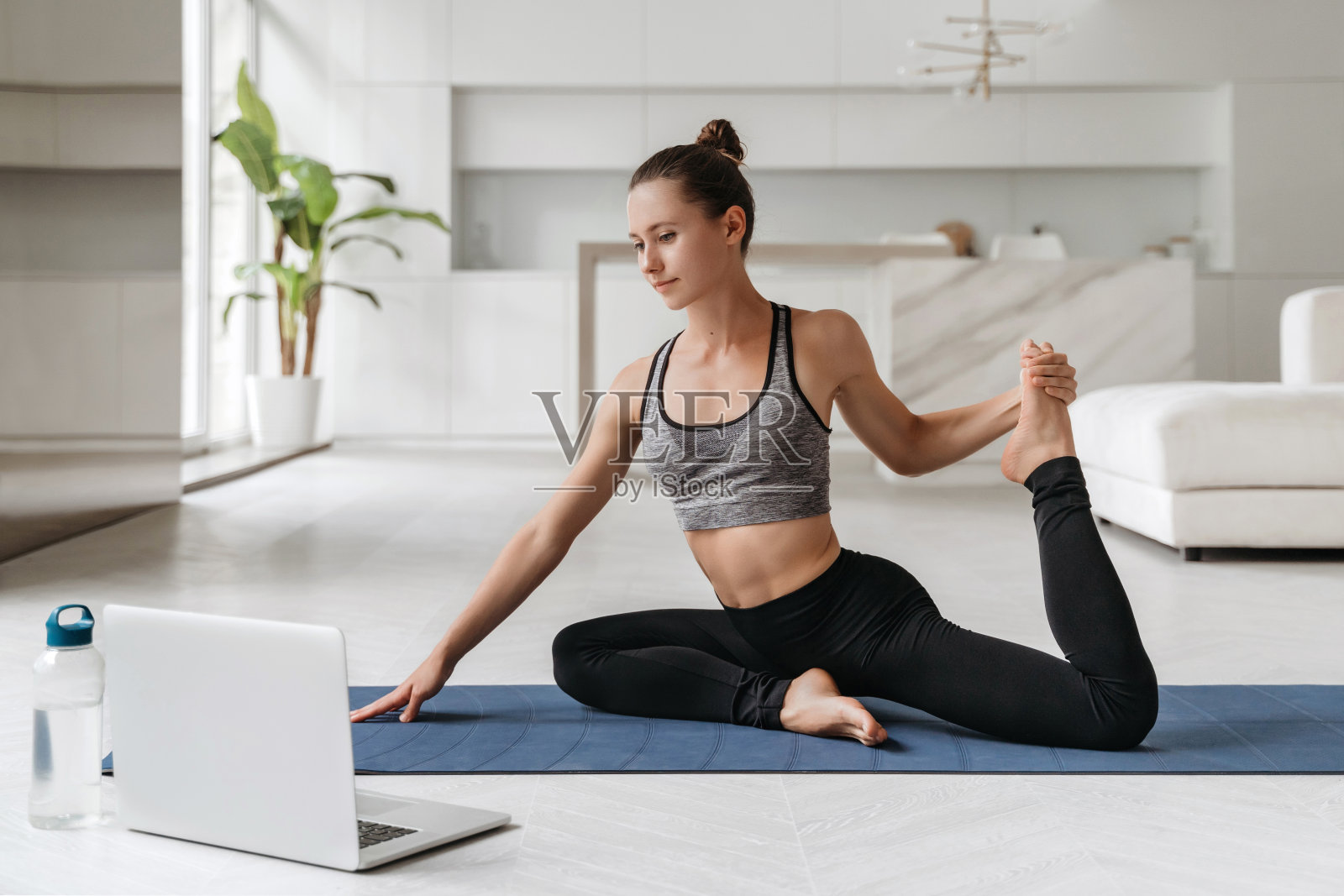 健身女孩在笔记本电脑上有个虚拟瑜伽课照片摄影图片